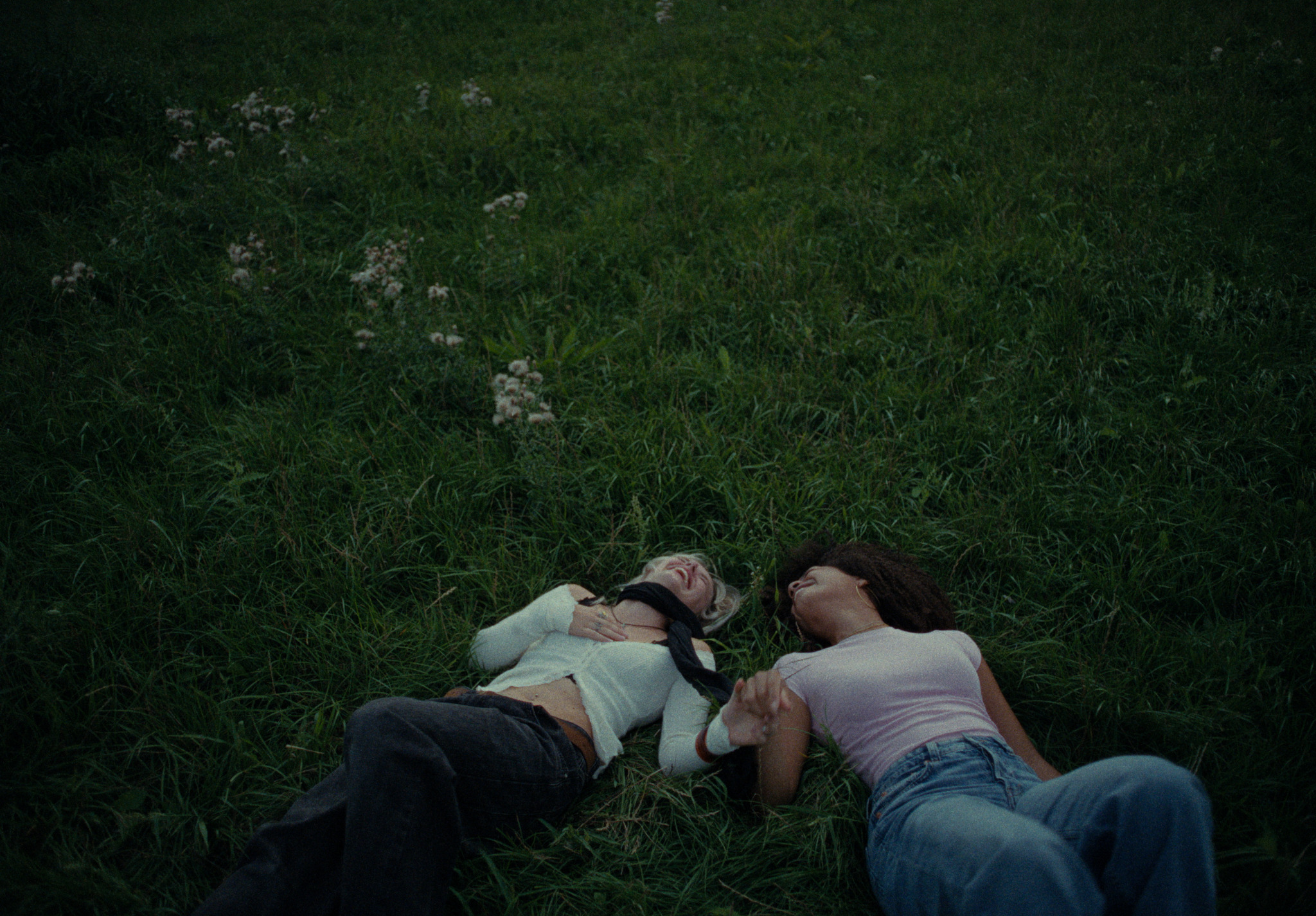 Two young women lying together in the grass