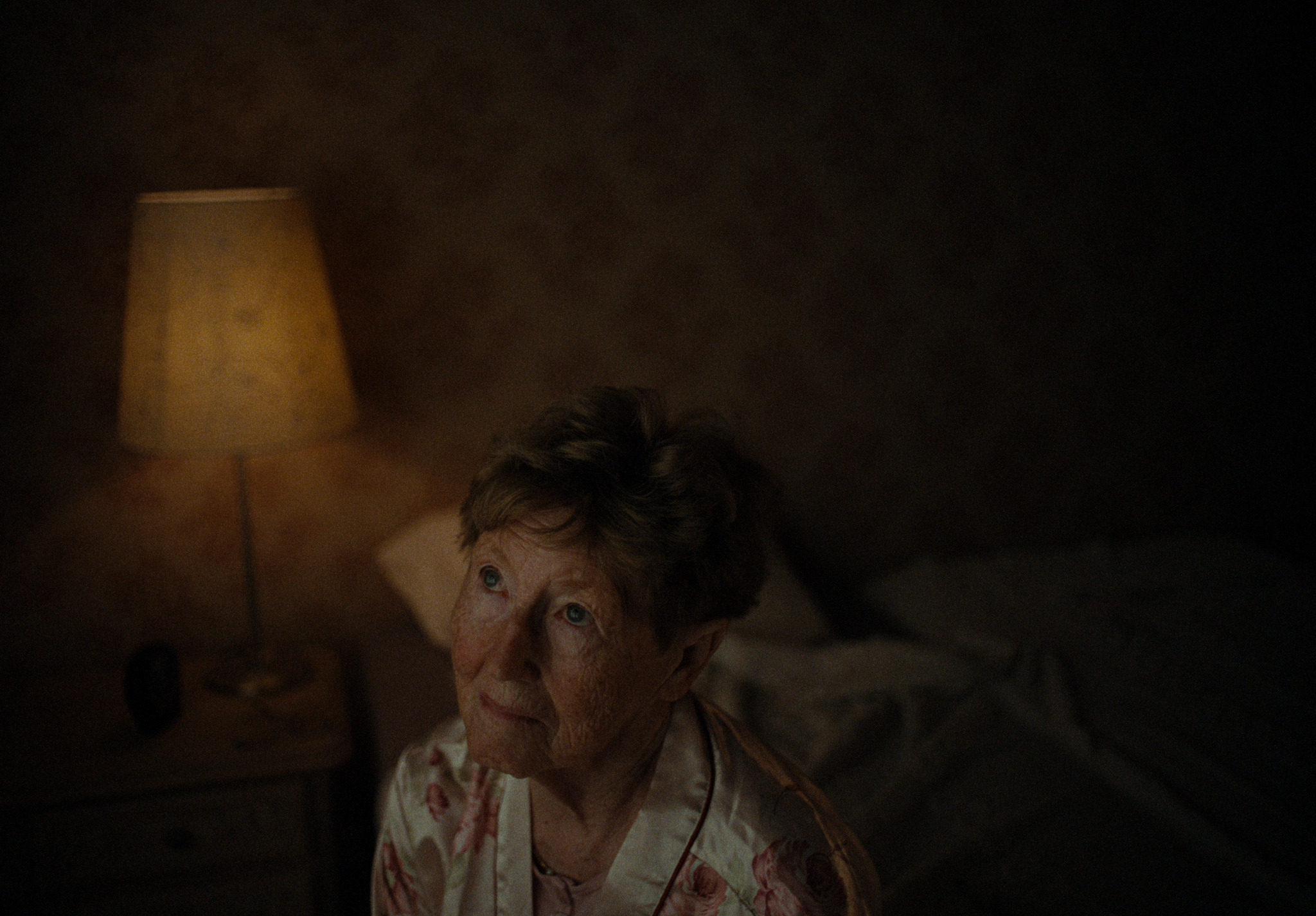 An older woman in a softly lit bedroom