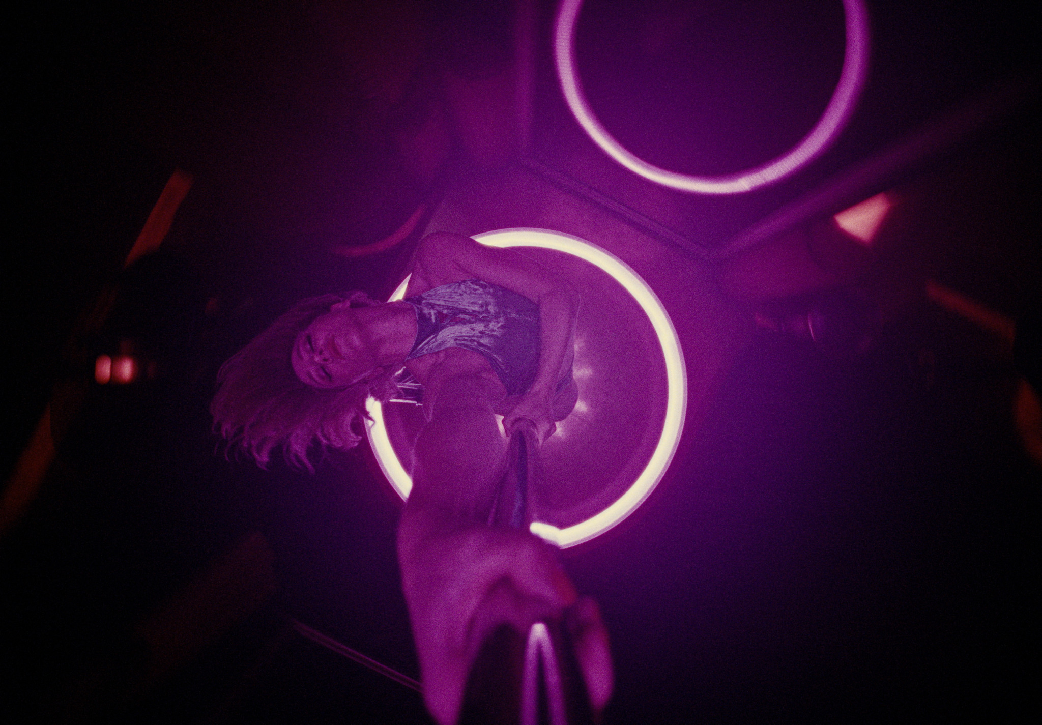 A dancer framed by violet neon lights