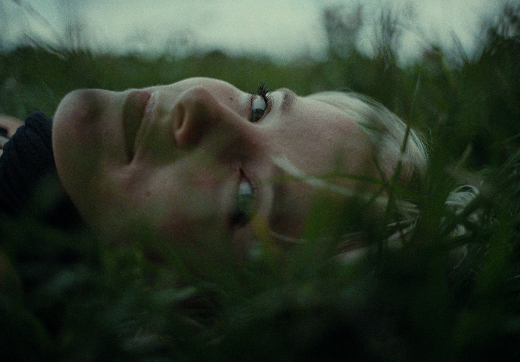 A close portrait of a young woman lying in grass
