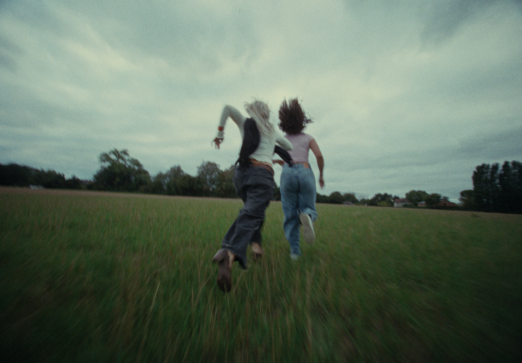 Two young women running through an open field
